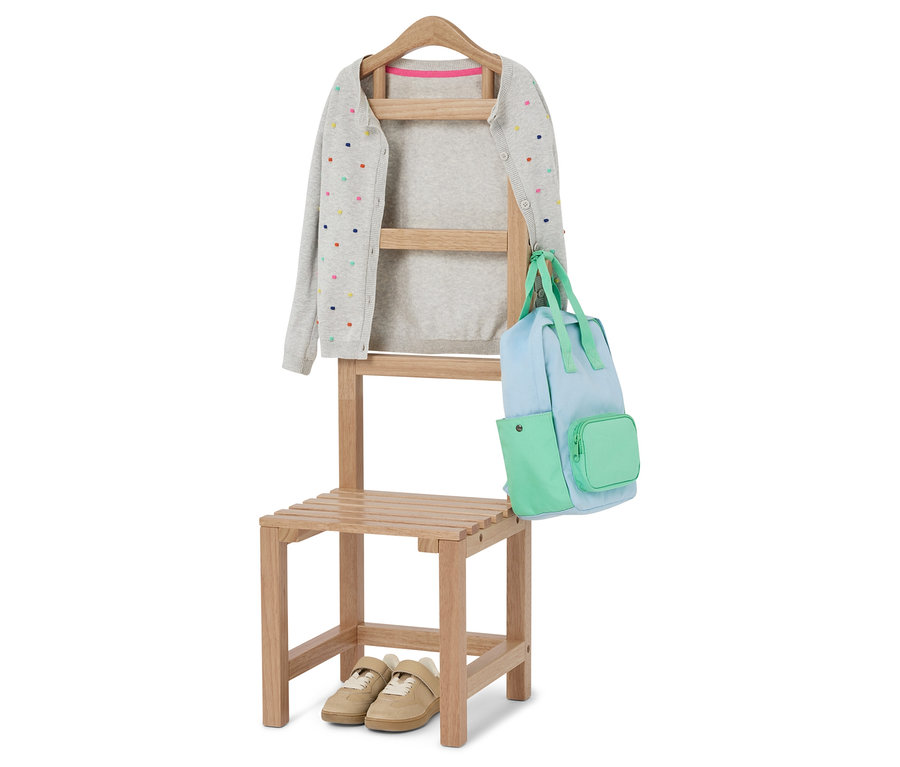 Szary kardigan w kolorowe kropki wisi na krześle z jasnoniebieską i zieloną torbą. Pod krzesłem stoją beżowe buty.