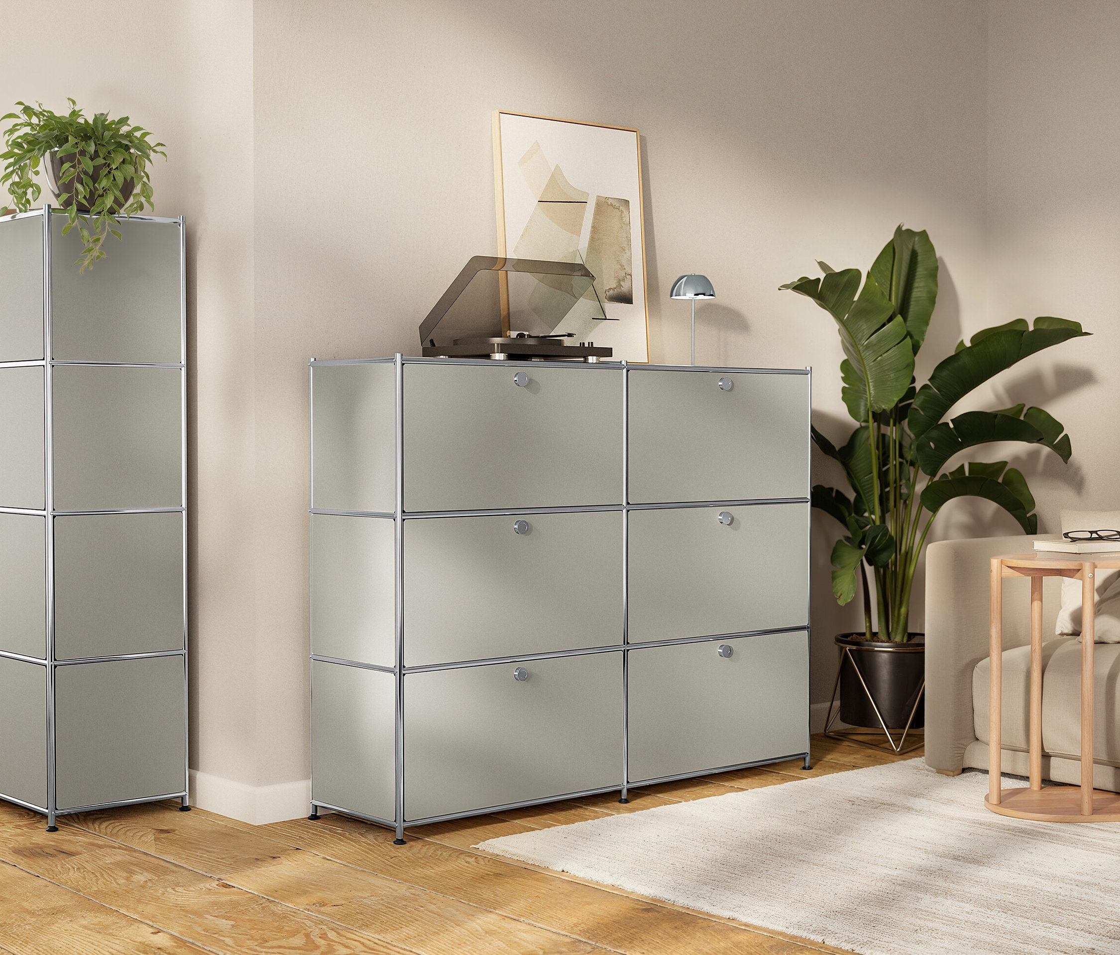 Pokój dzienny z modułowymi, szarymi szafkami do przechowywania, gramofonem, roślinami doniczkowymi i sofą.