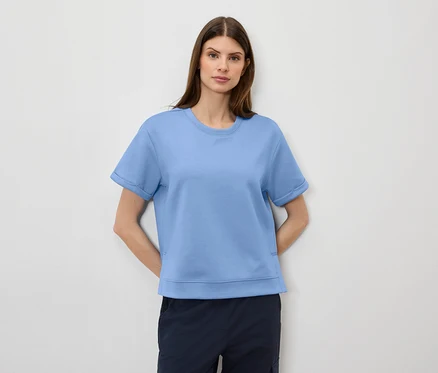Kobieta ma na sobie jasno-niebieski T-shirt i granatowe szorty.