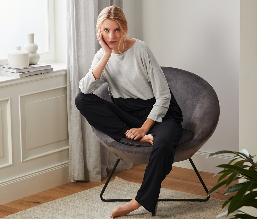 Blondynka siedzi w fotelu w dresie domowym.