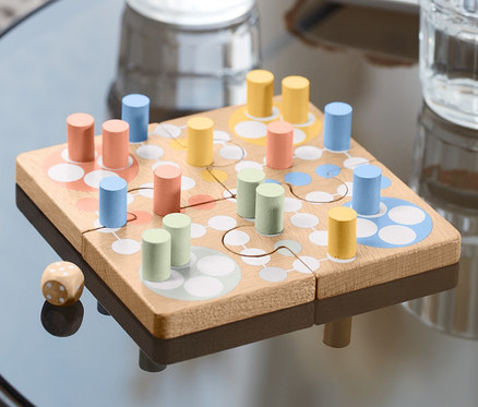Na stole leży gra Puzzle Ludo z kolorowymi pionkami i kostką.