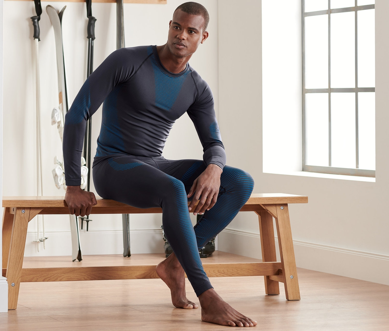 Mężczyzna siedzi na ławce i ma na sobie bezszwową bieliznę funkcyjną.
