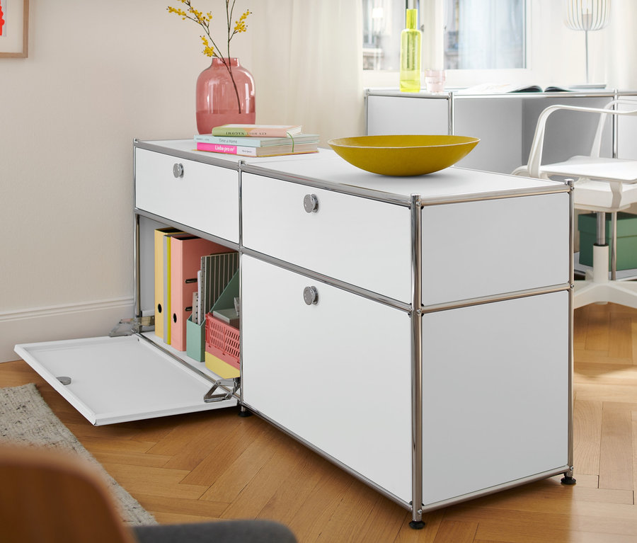 Białe metalowe biurko »CN3« z klapą i szafka typu sideboard „CN3” z szufladami i drzwiami w pokoju.