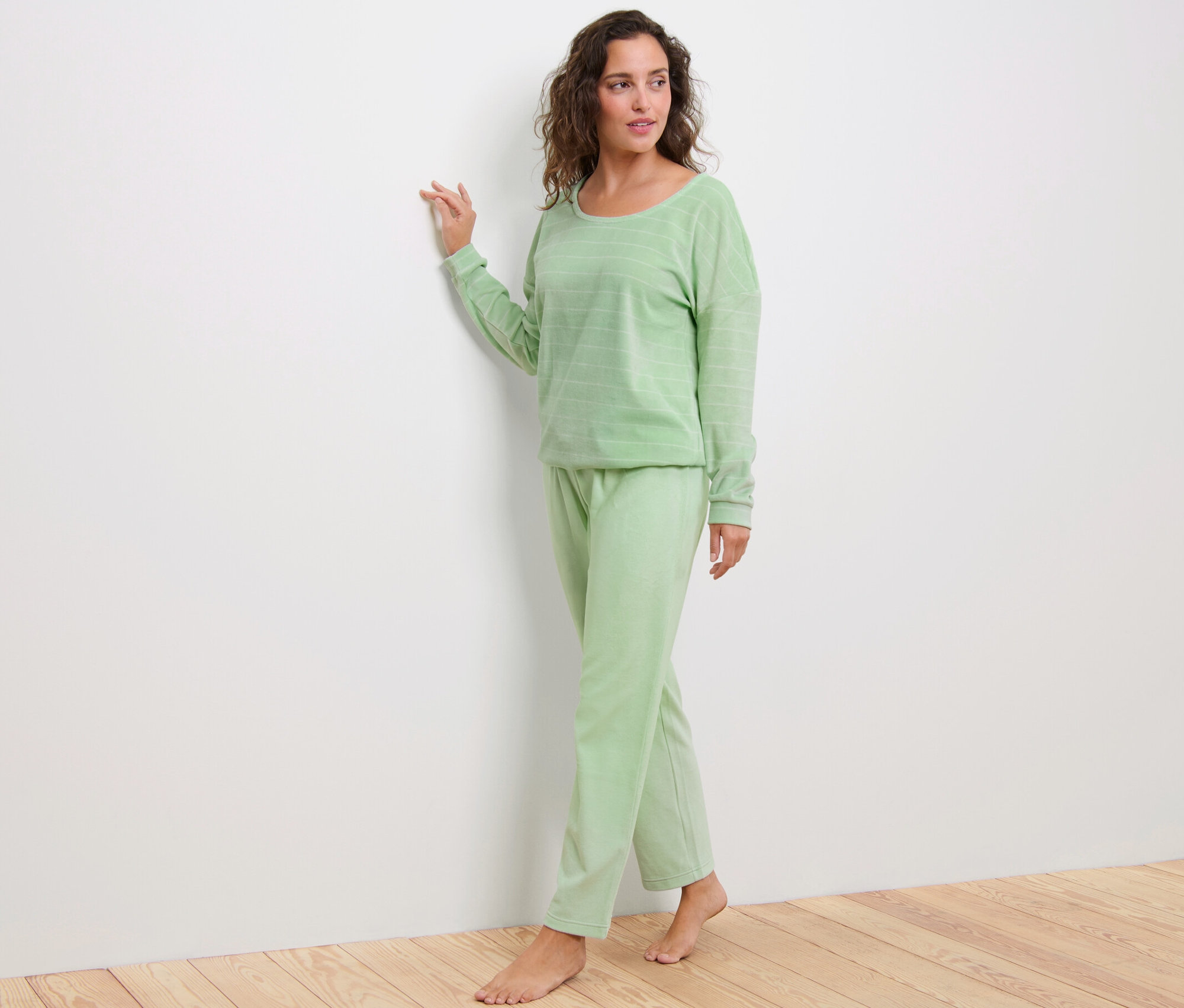 Kobieta stoi w zielonej piżamie z weluru.