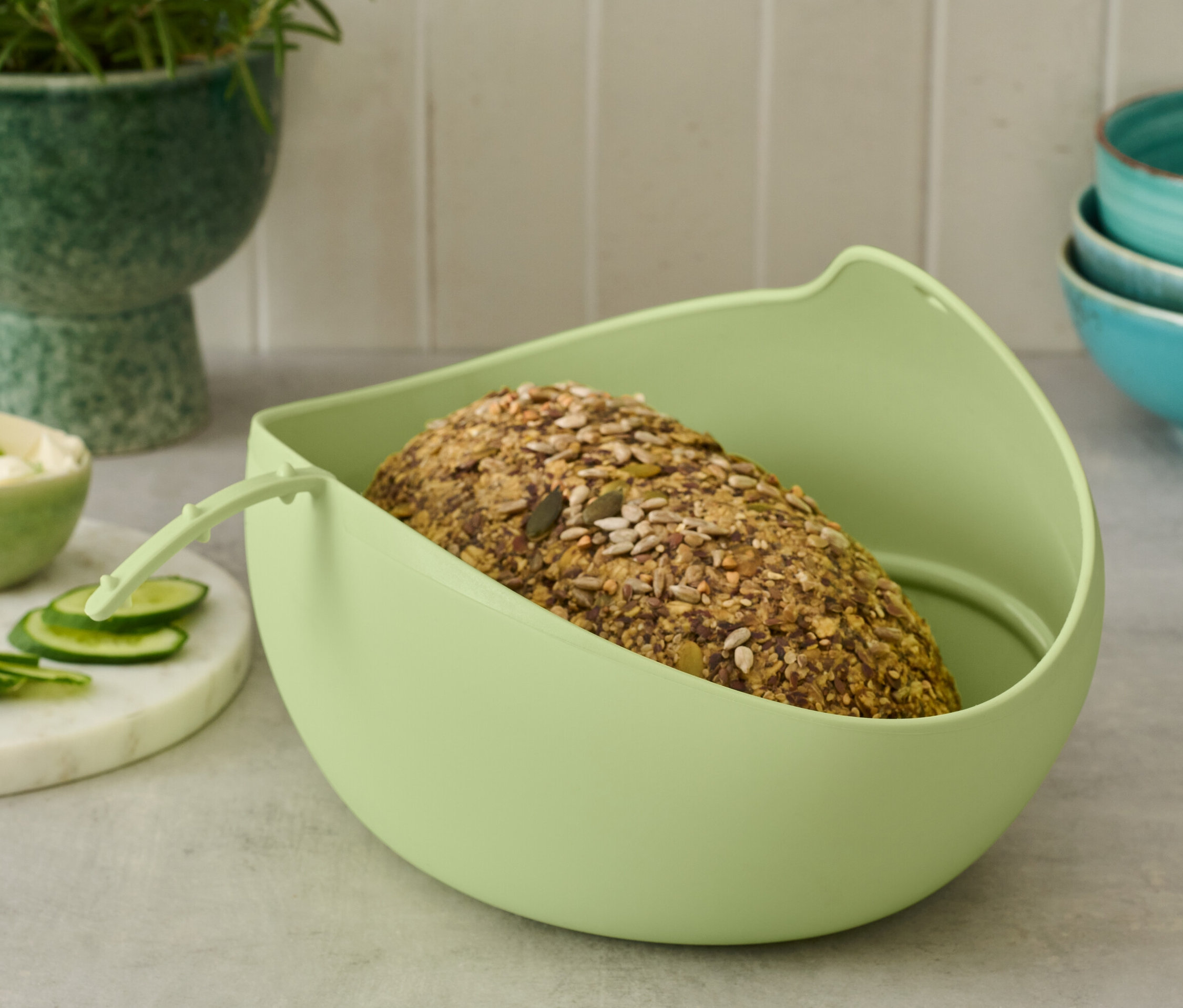 Chleb leży w jasnozielonej formie do pieczenia chleba.