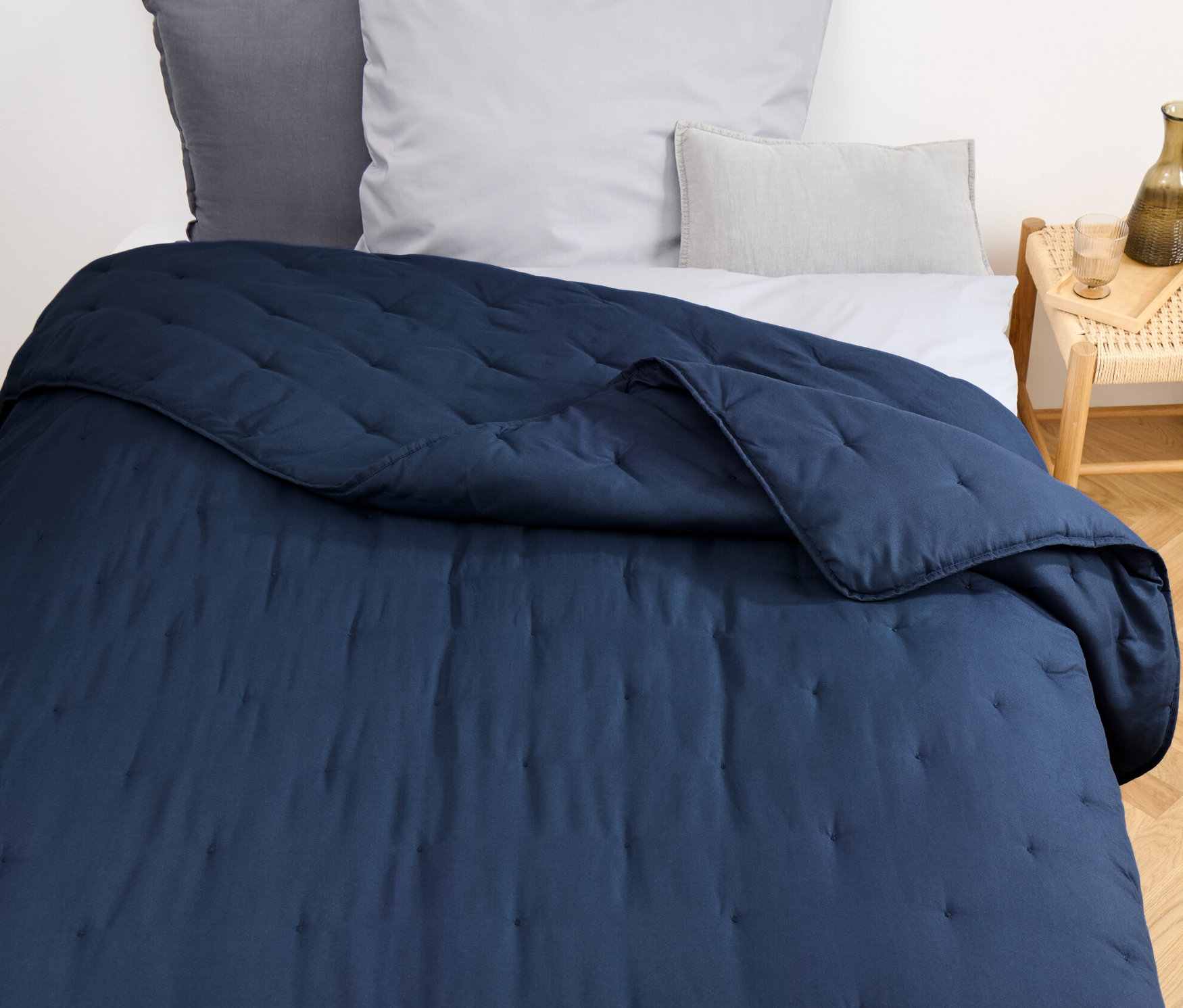 Na łóżku leży niebieska narzuta.