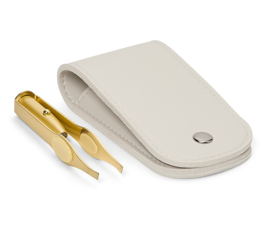 Złota pęseta leży obok otwartego, białego etui.
