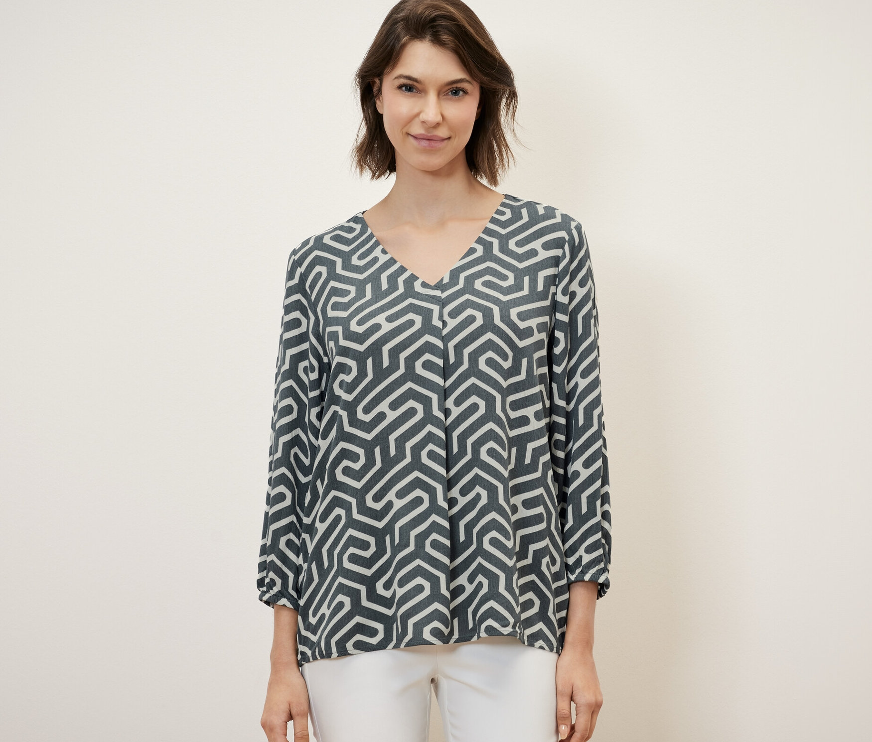 Kobieta ma na sobie bluzkę i białe spodnie.