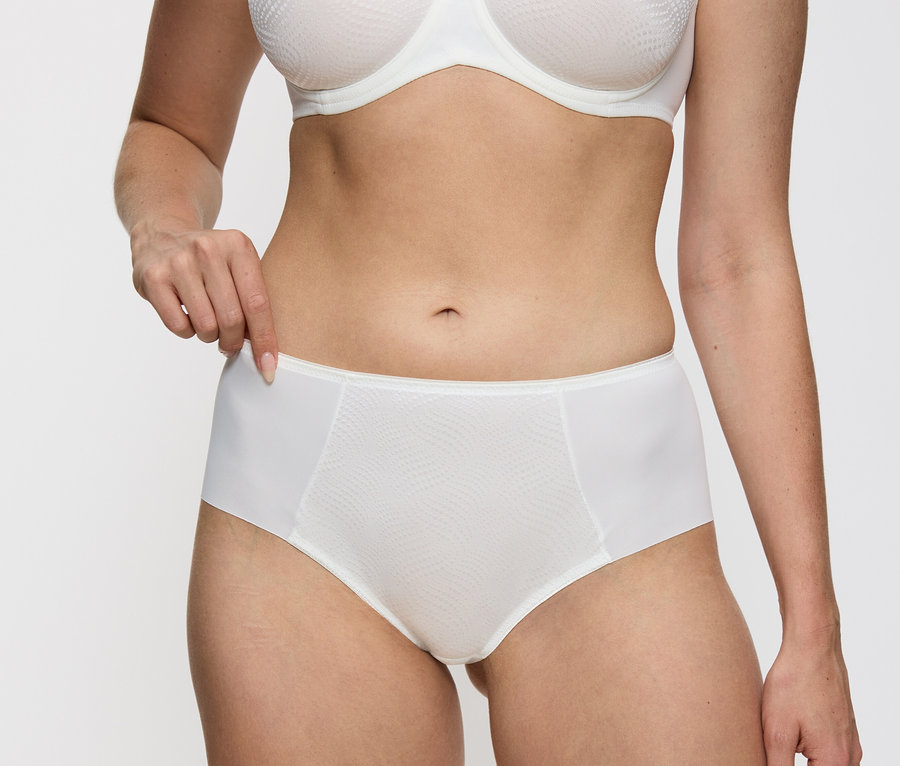 Kobieta ma na sobie figi typu hipster Triumph Essential „Minimizer Hipster X” w kolorze waniliowym.