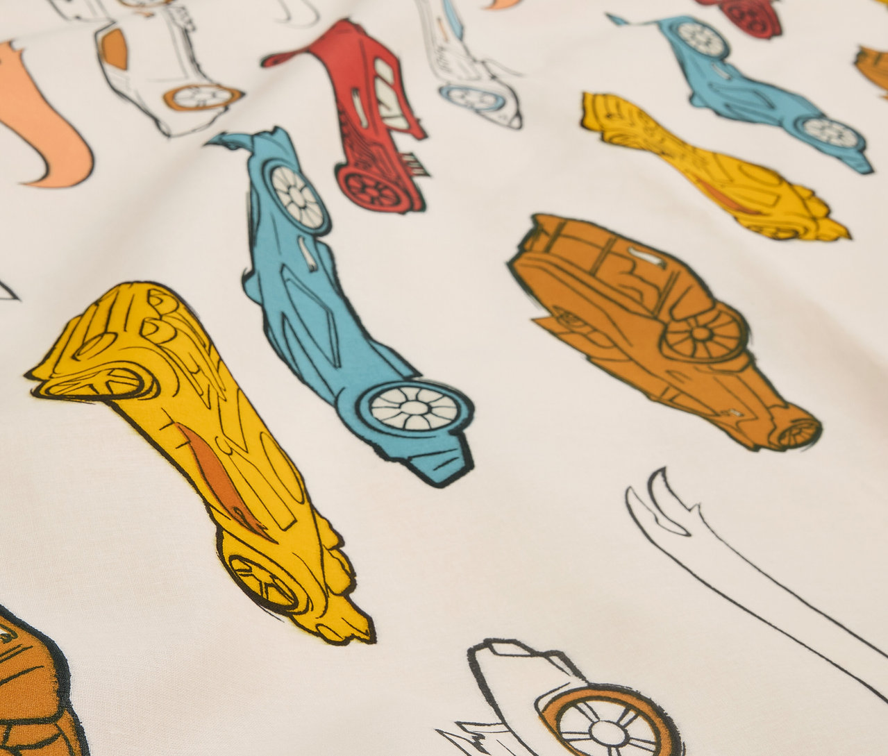 Zbliżenie na tkaninę z nadrukiem stylizowanych samochodów wyścigowych w różnych kolorach.