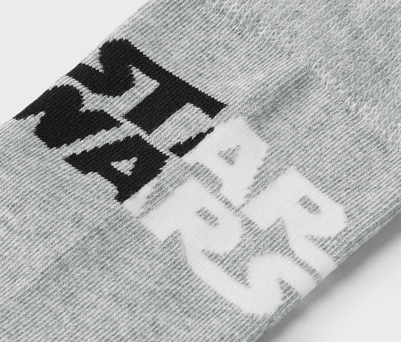 Zbliżenie na szarą skarpetę z czarnym i białym napisem.