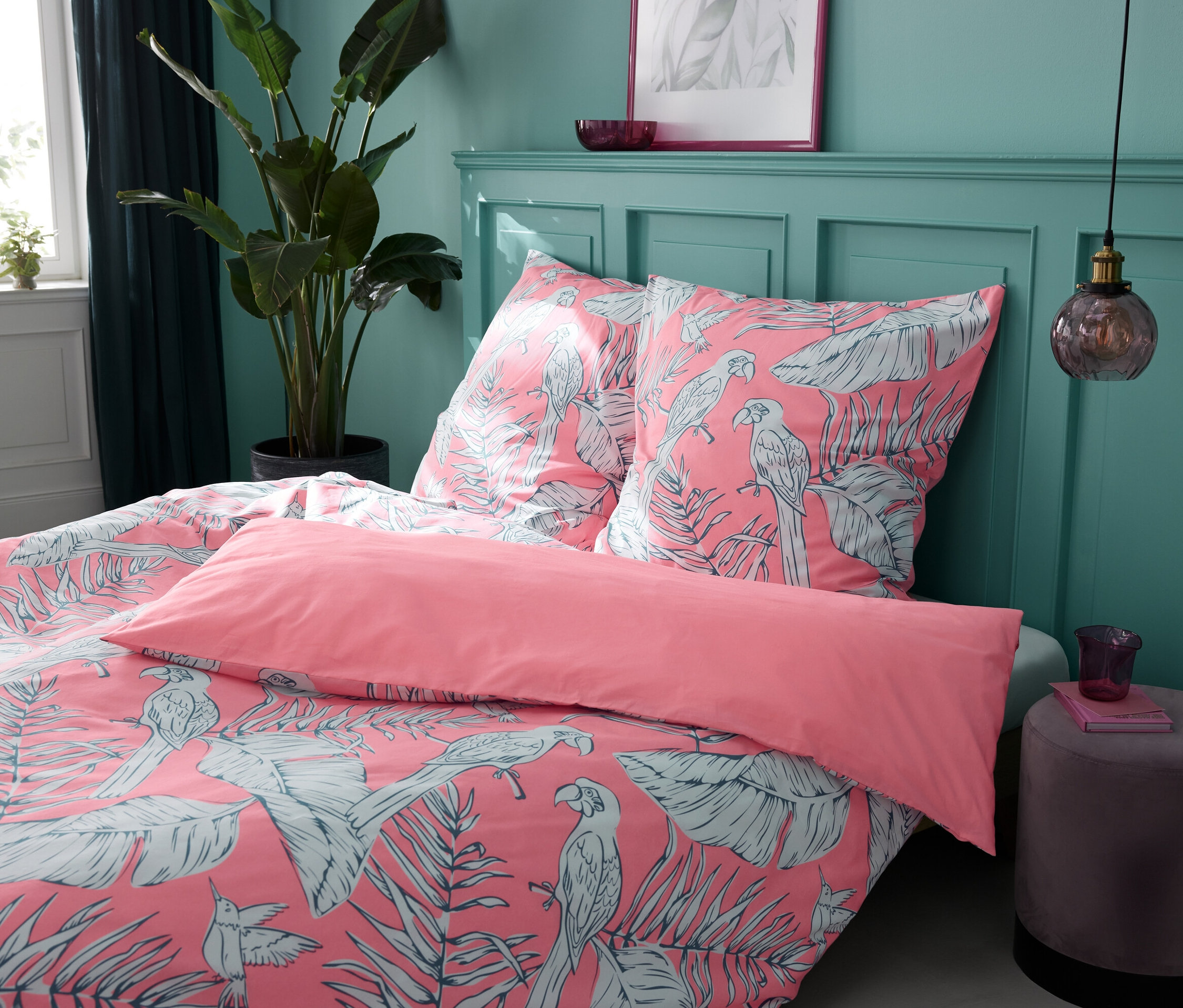 Cztery komplety pościeli z bawełny renforcé Tropical Rose w różnych rozmiarach na łóżku.