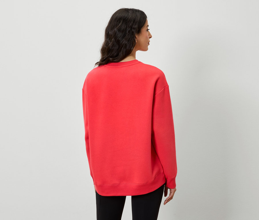 Widok z tyłu kobiety w czerwonej bluzie i czarnych spodniach.