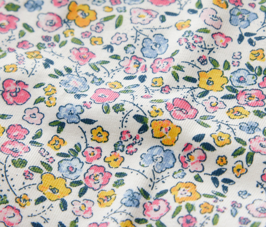 Zbliżenie na legginsy dziecięce z kwiatowym wzorem w odcieniach różu, błękitu i żółci.