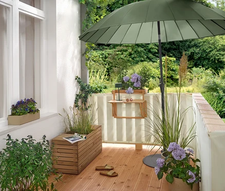 Na balkonie stoi zielony parasol Leco Shanghai (Ø 270 cm) w płaskiej podstawie Leco (Ø ok. 60 cm).
