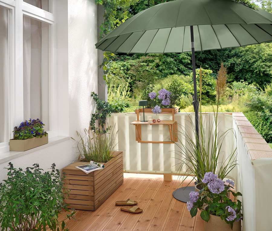 Na balkonie stoi zielony parasol Leco Shanghai (Ø 270 cm) w płaskiej podstawie Leco (Ø ok. 60 cm).