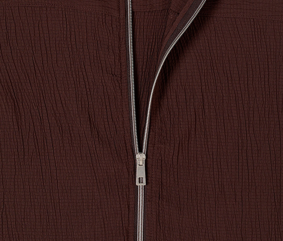 Zbliżenie na rozpiętą kurtkę bomberkę CECIL w kolorze ciemnobrązowym z srebrnym zamkiem błyskawicznym.