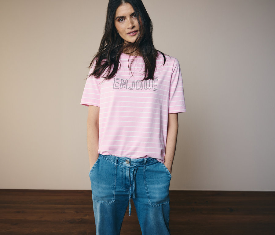 Kobieta w dżinsach i różowo-białej koszulce CECIL z napisem ENJOUE.