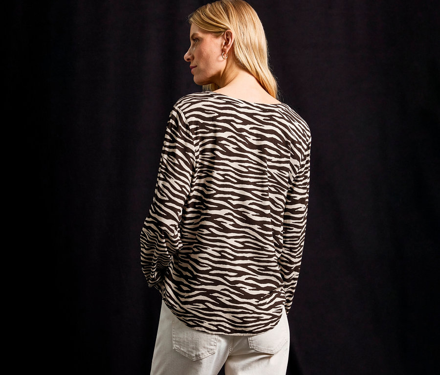 Blondynka w bluzce Street One w zebrę i jasnych jeansach.