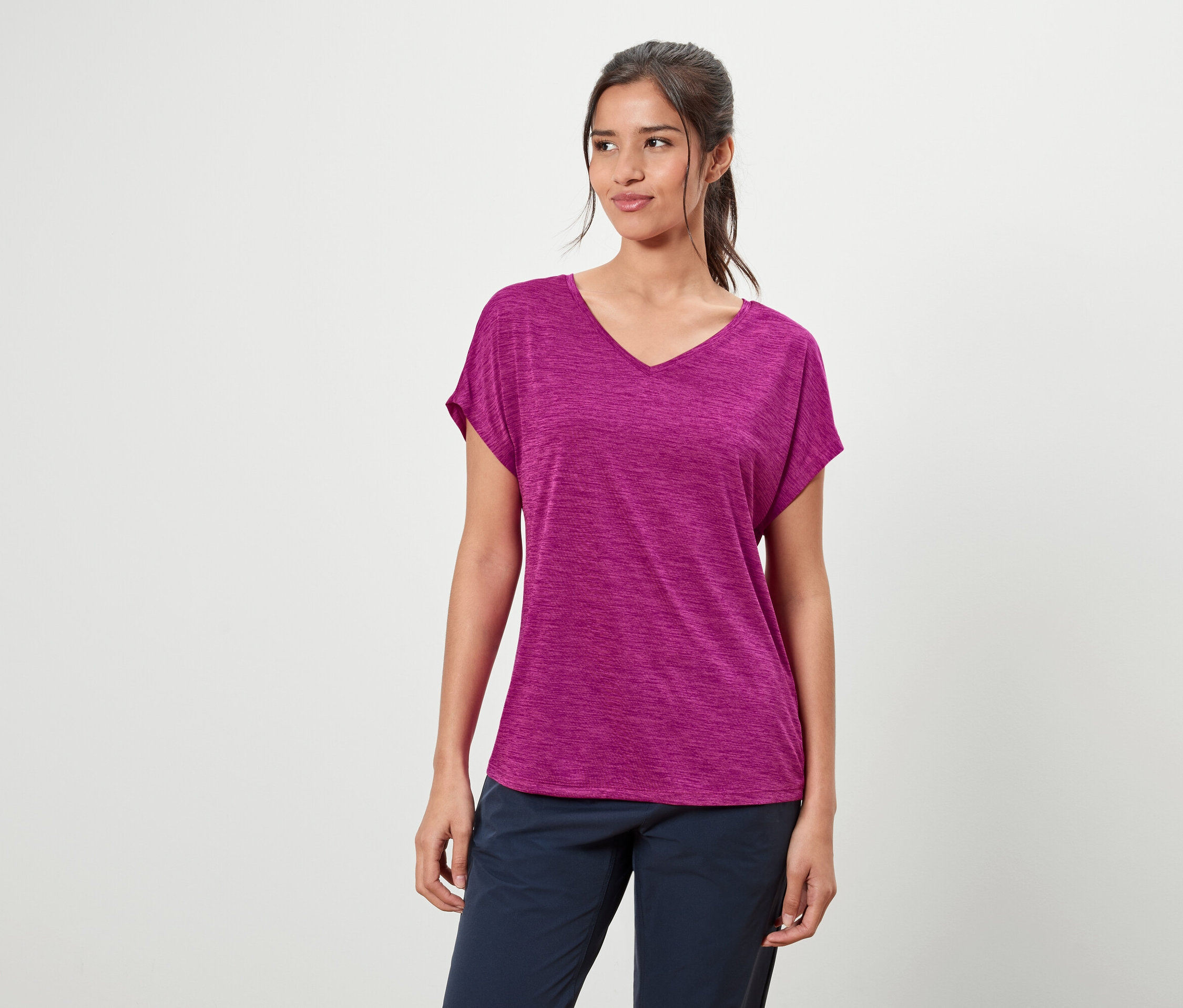 Kobieta ma na sobie fioletową koszulkę i niebieskie spodnie.