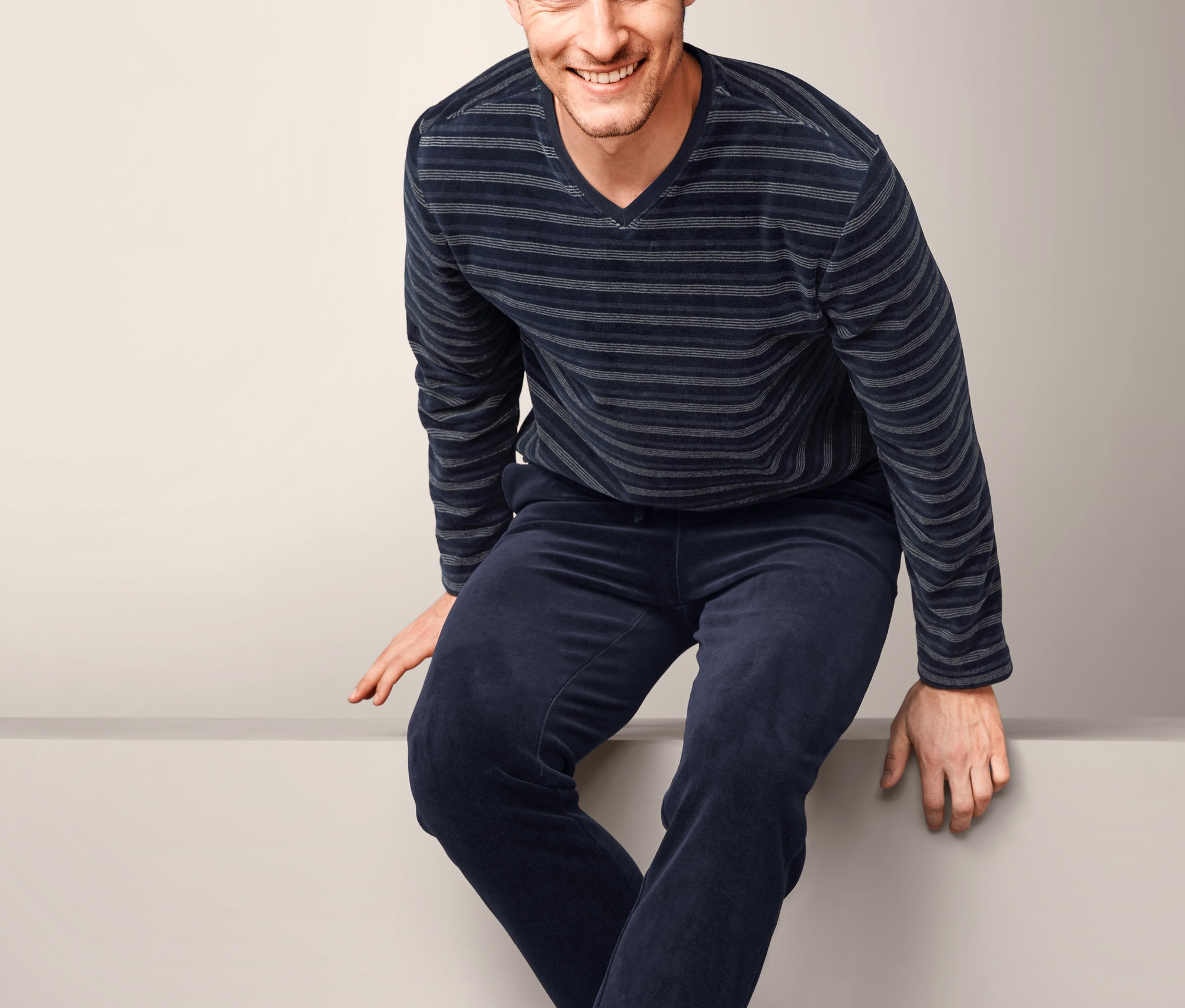 Mężczyzna siedzi i ma na sobie piżamę męską z weluru z bawełną ekologiczną.