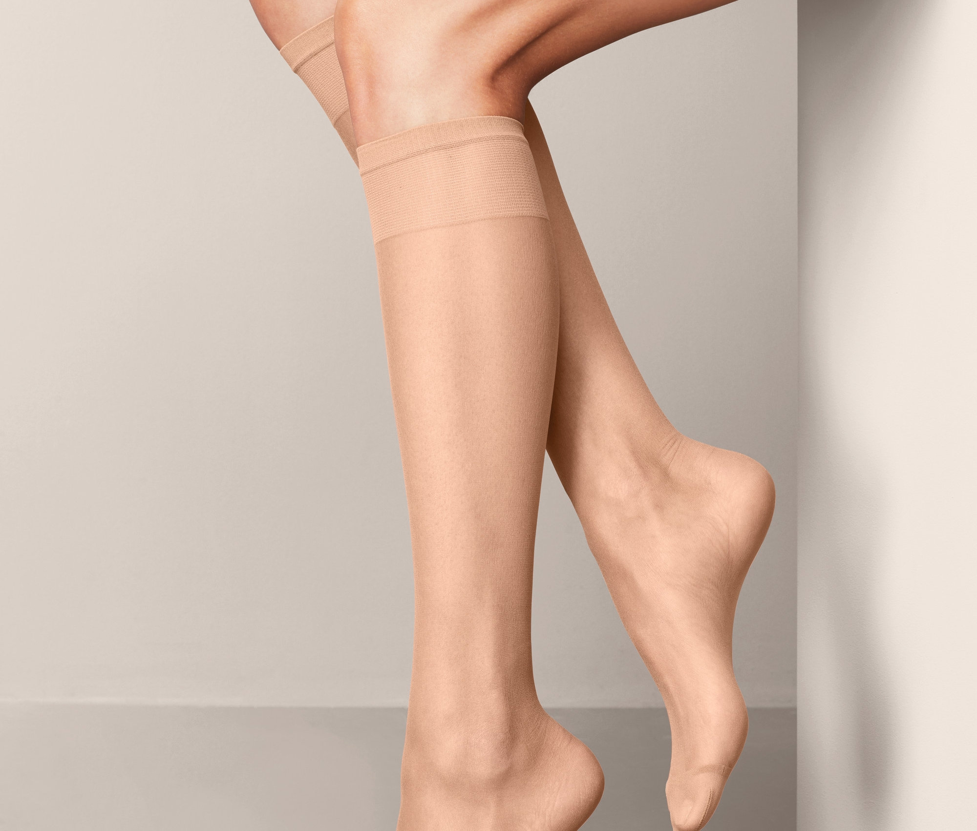 Nogi kobiety w beżowych podkolanówkach.