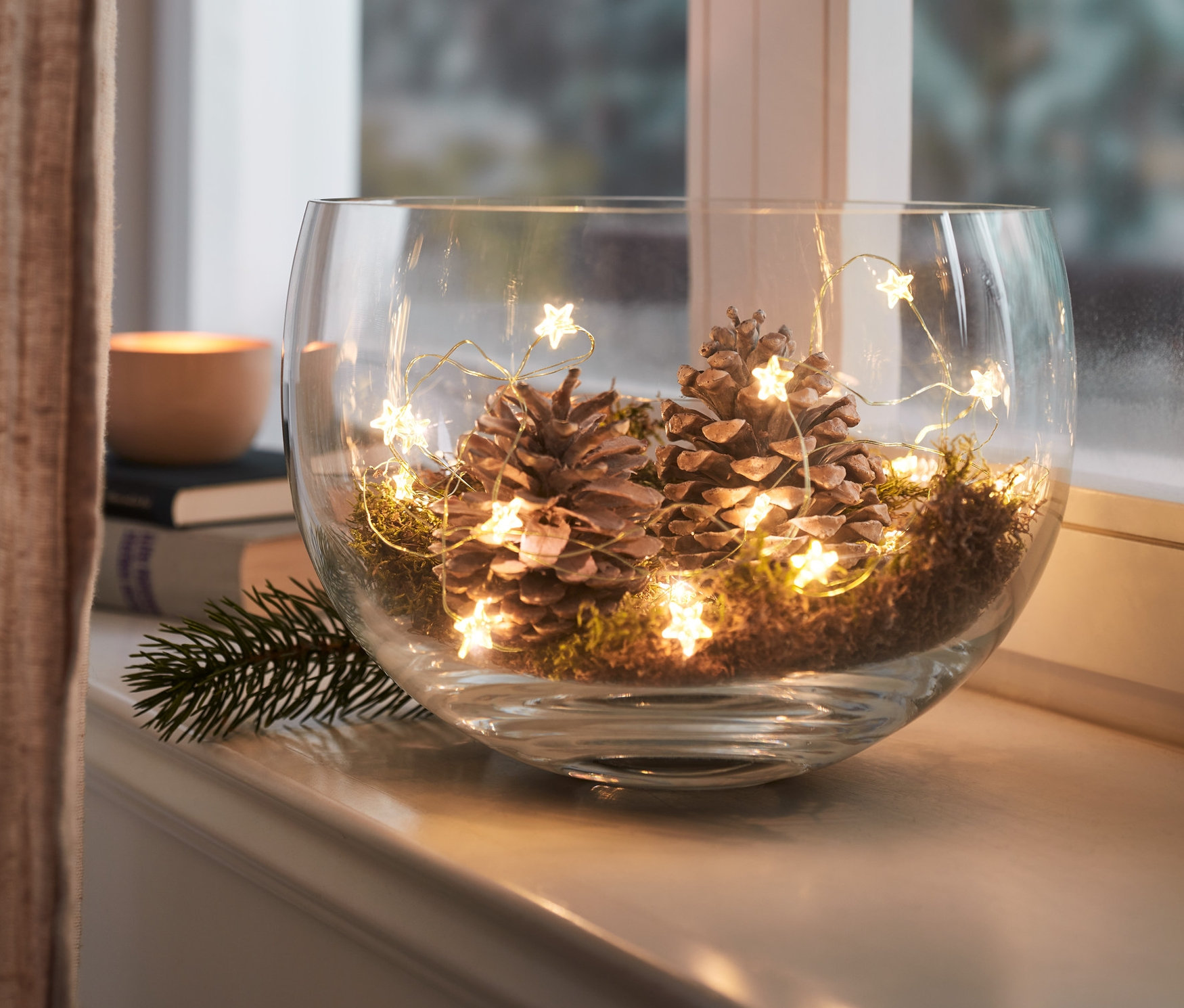 Szklana misa ze szyszkami, mchem i łańcuchem świetlnym z diodami LED mikro, »gwiazdki«.