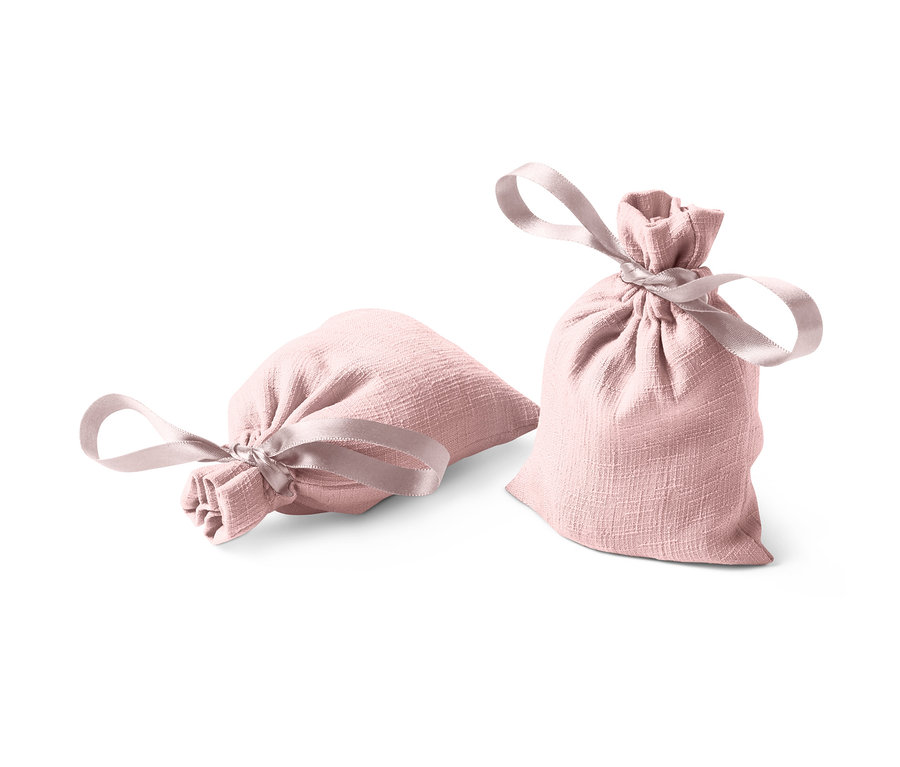 Dwa woreczki zapachowe, jeden leży, drugi stoi, oba różowe z kokardką.