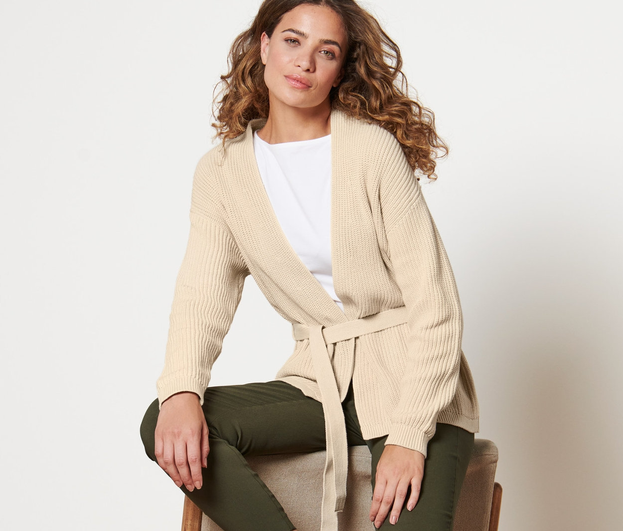 Kobieta siedzi na krześle i ma na sobie kardigan kopertowy.