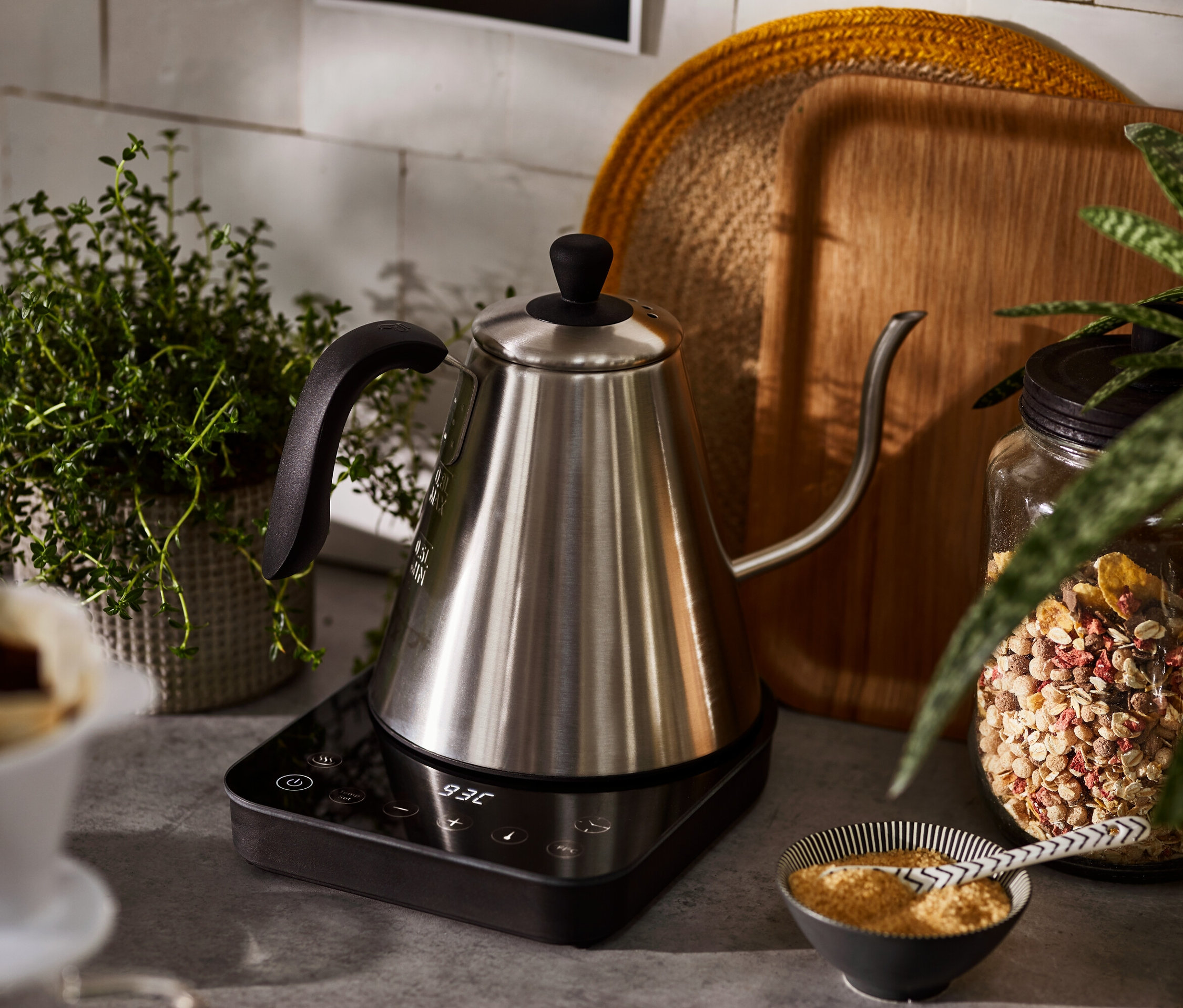 Elektryczny czajnik typu konewka stoi na podstawie.