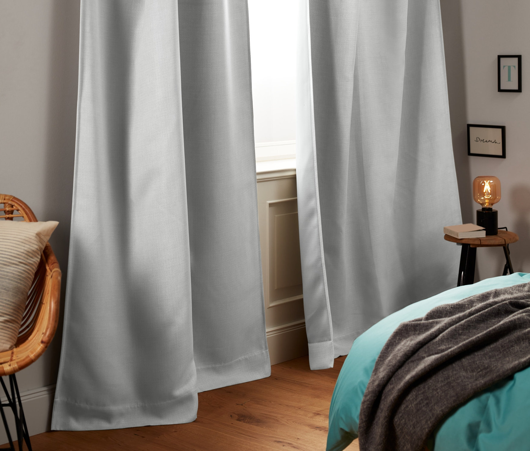 Dwie zasłony zaciemniające wiszą w oknie w sypialni.