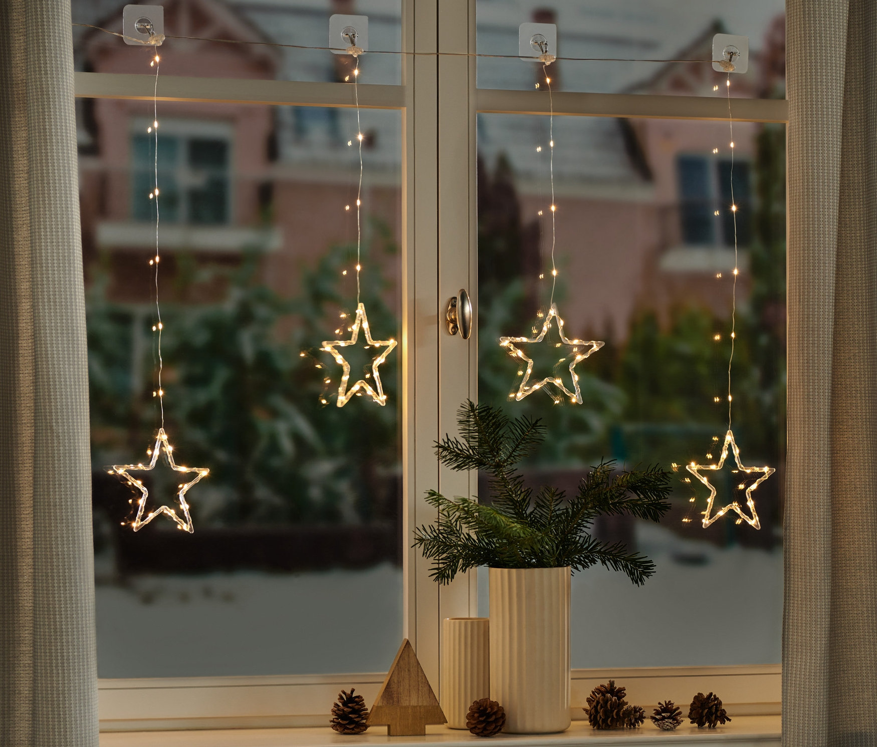 Cztery kurtyny świetlne LED z gwiazdami wiszą w oknie.