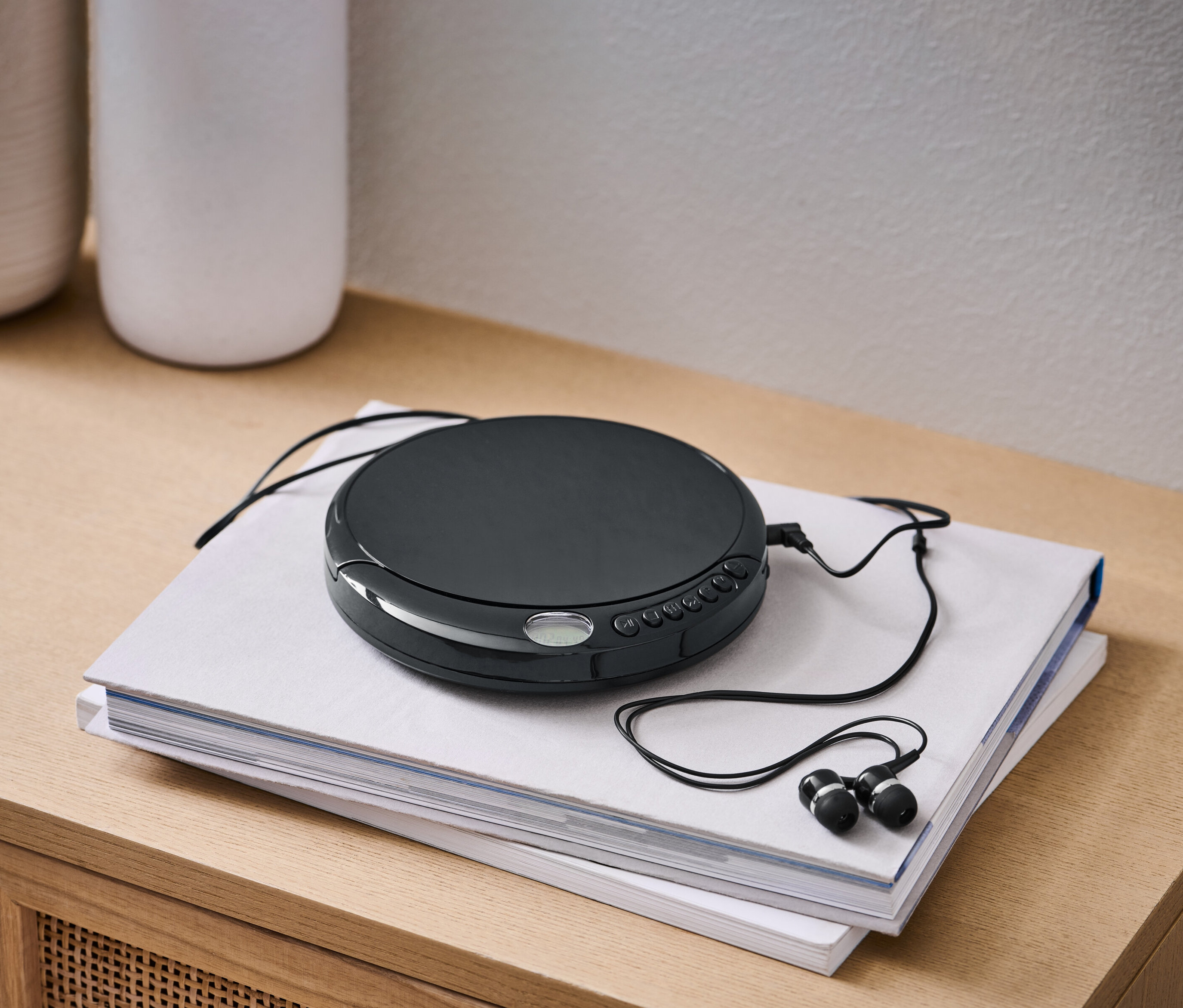 Czarny przenośny odtwarzacz CD z czarnymi słuchawkami leży na dwóch książkach.