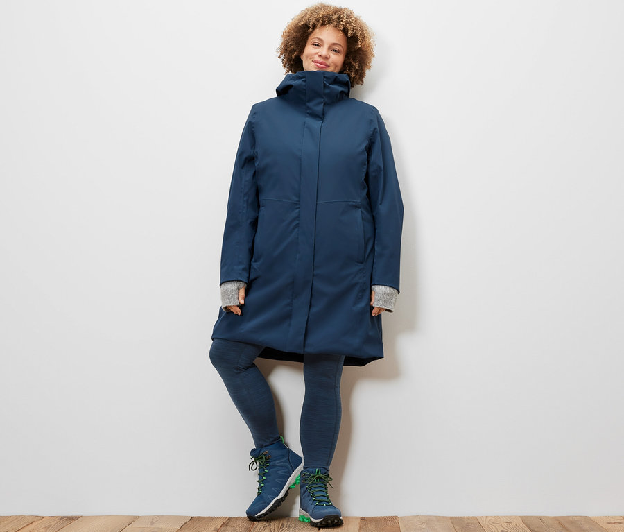 Kobieta pozuje w legginsach sportowych i płaszczu funkcyjnym 3 w 1 z kamizelką.