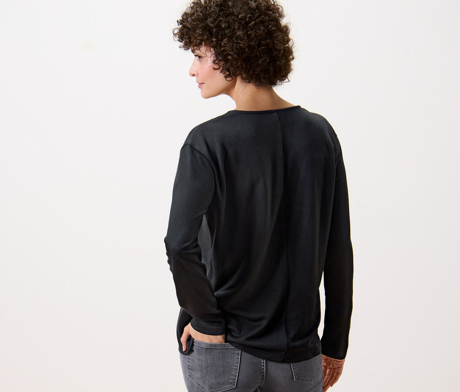 Kobieta tyłem do kamery ma na sobie czarną bluzkę.