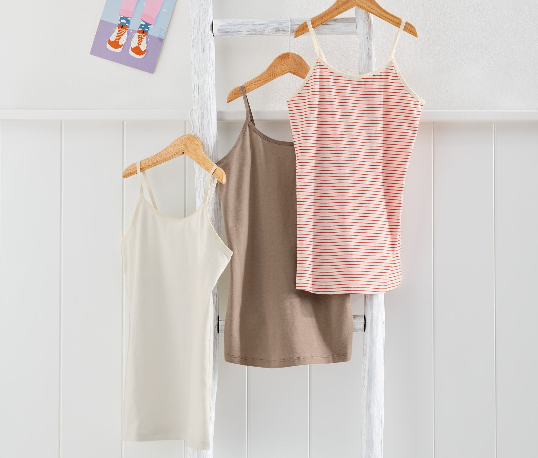 Trzy podkoszulki na białej drabinie.