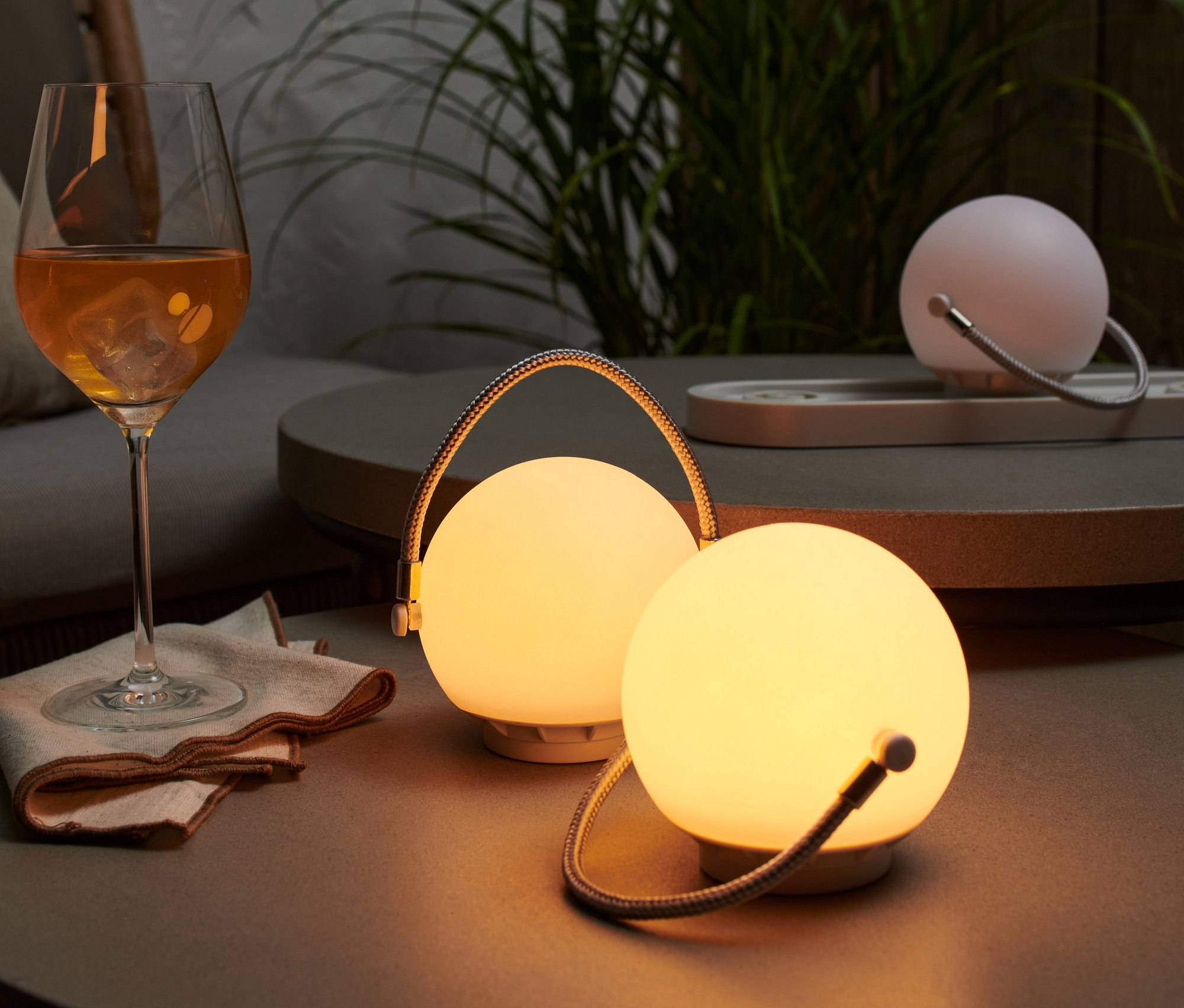 Na stoliku stoi zestaw akumulatorowych lampek stołowych obok szklanki z napojem.