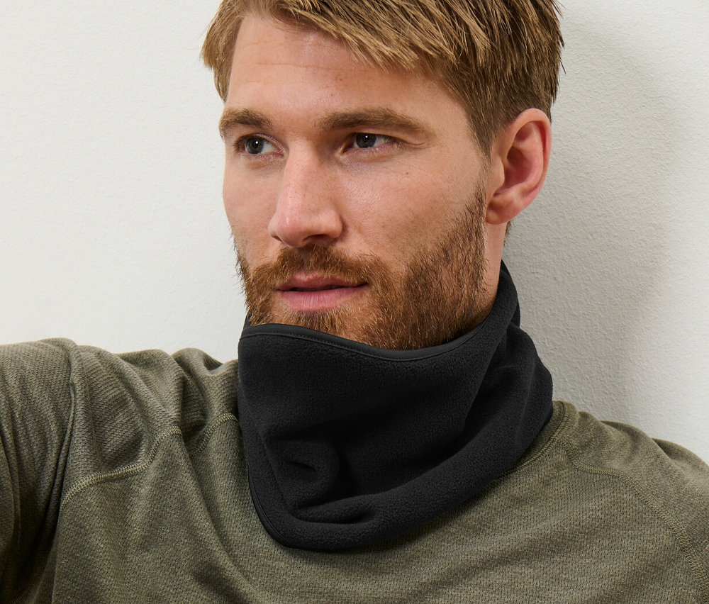 Mężczyzna o brązowych włosach siedzi i ma na sobie czarny kołnierz z polaru.