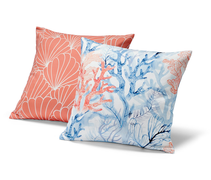Dwie poszewki na poduszki dekoracyjne: jedna koralowa z białym geometrycznym wzorem, druga z niebieskimi i koralowymi koralowcami.