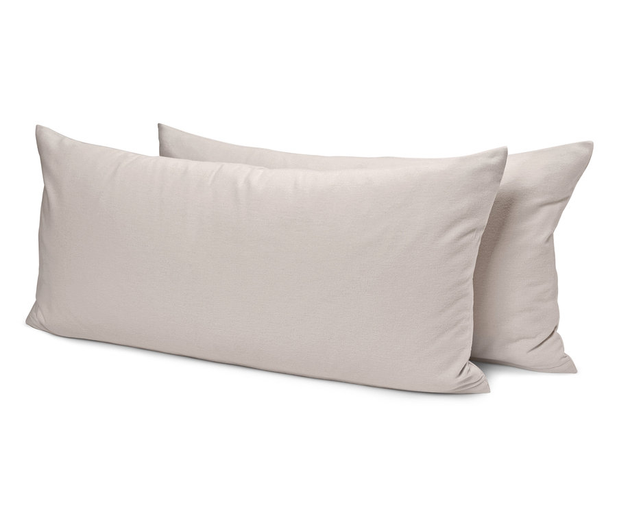 Dwie kremowe poduszki leżą jedna na drugiej.