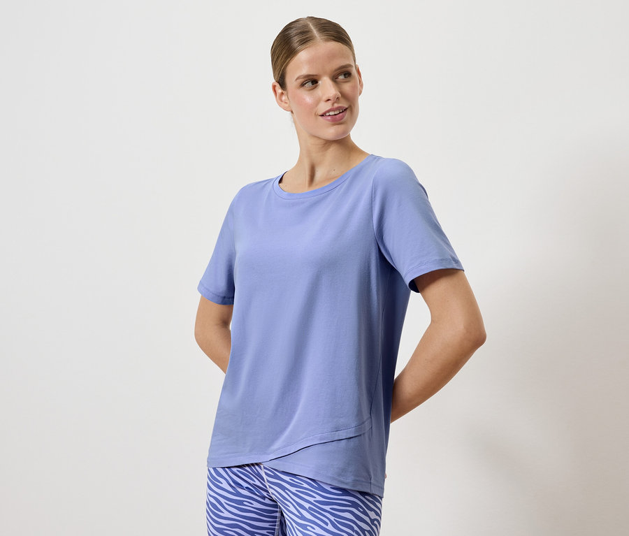 Kobieta pozuje w niebieskiej koszulce i spodniach w zwierzęcy wzór.