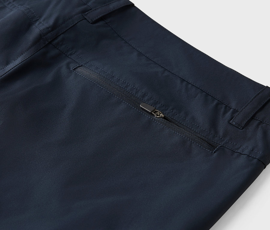 Zdjęcie zbliżeniowe granatowych spodni z kieszenią na zamek błyskawiczny.