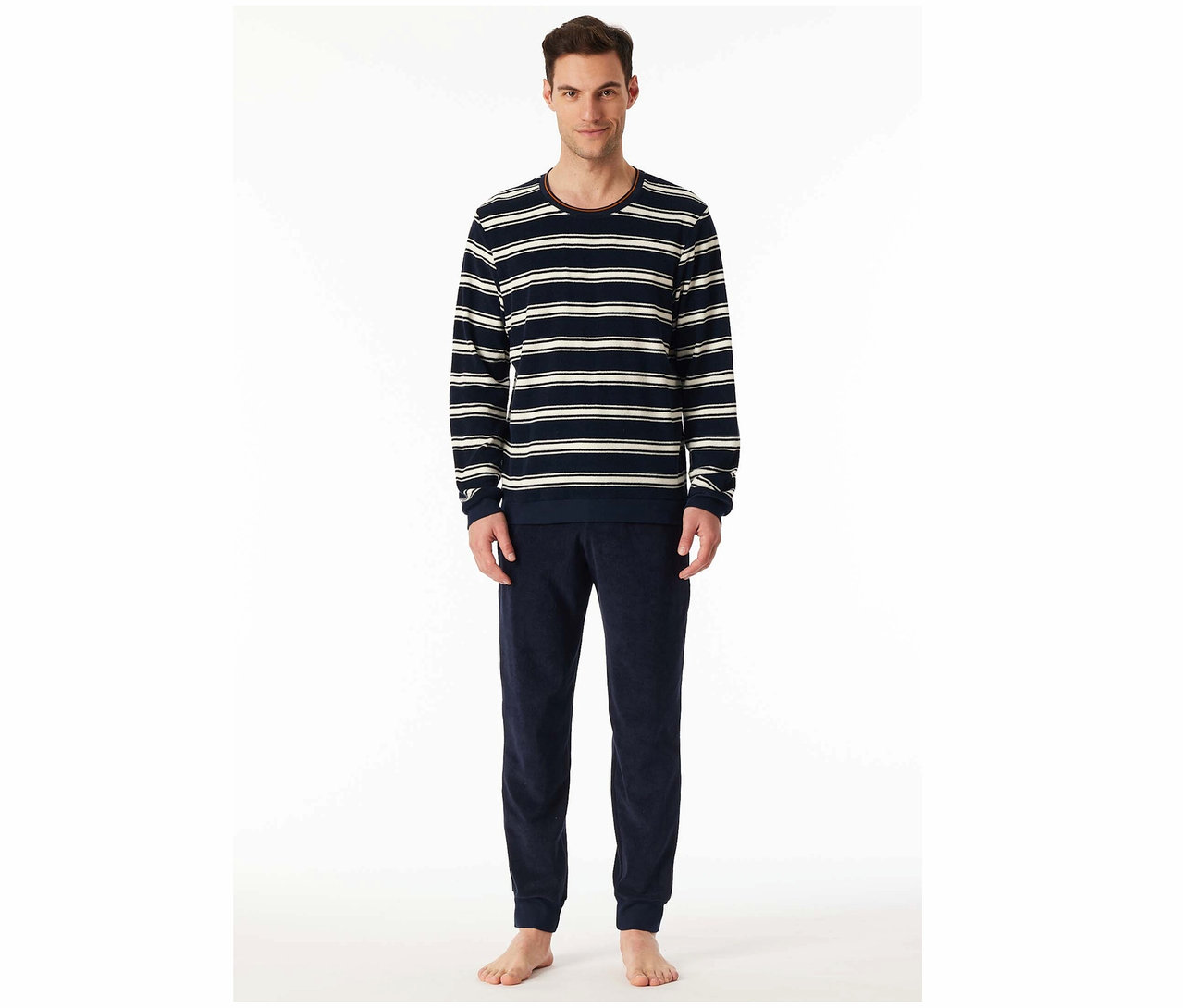 Mężczyzna stoi ubrany w koszulkę z długim rękawem w paski i granatowe welurowe spodnie do biegania.