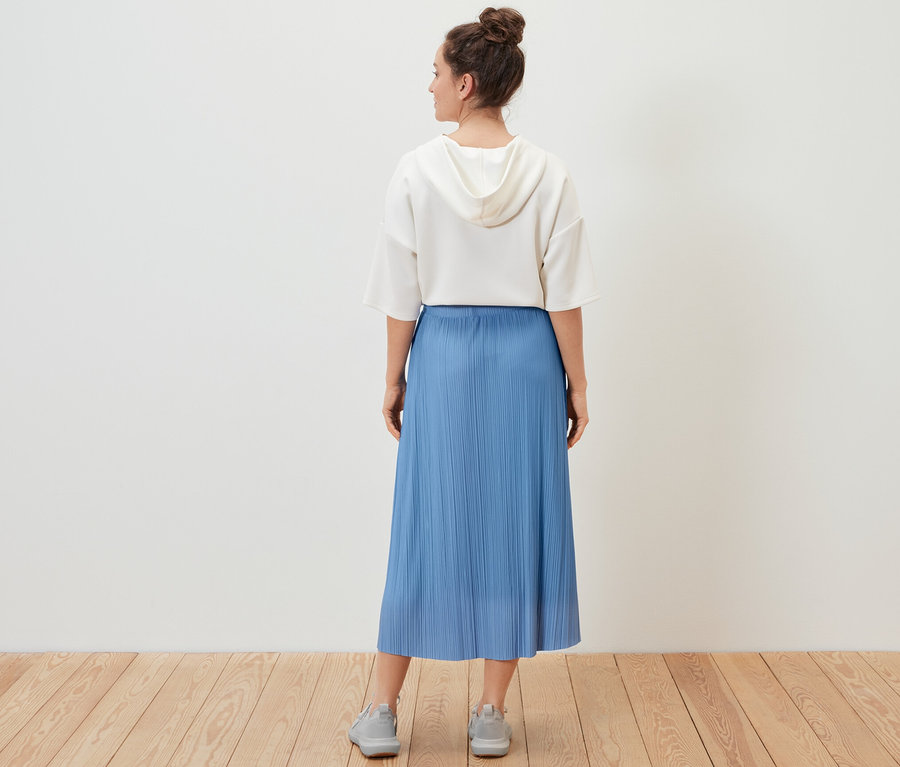 Kobieta ma na sobie spódnicę plisowaną.