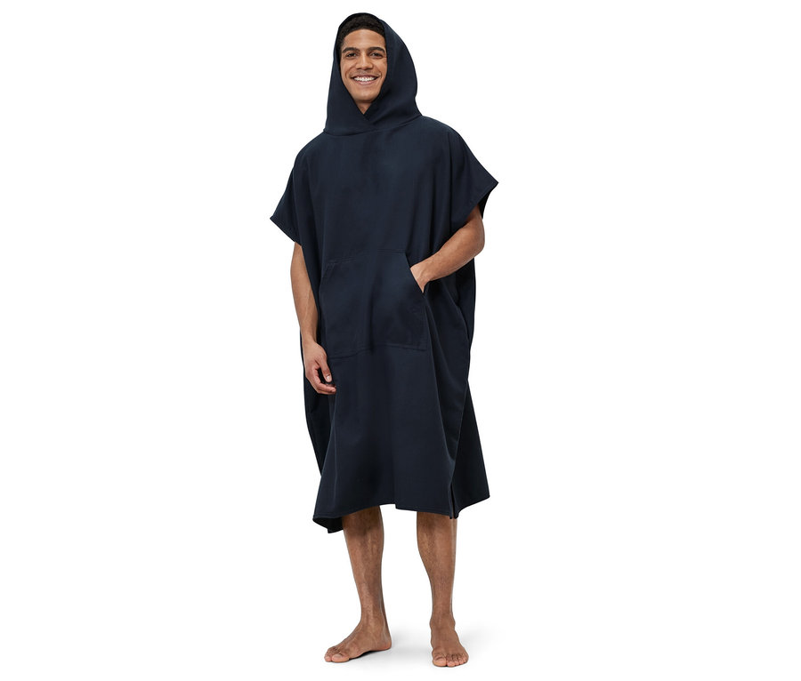 Mężczyzna stoi i ma na sobie niebieskie poncho kąpielowe.