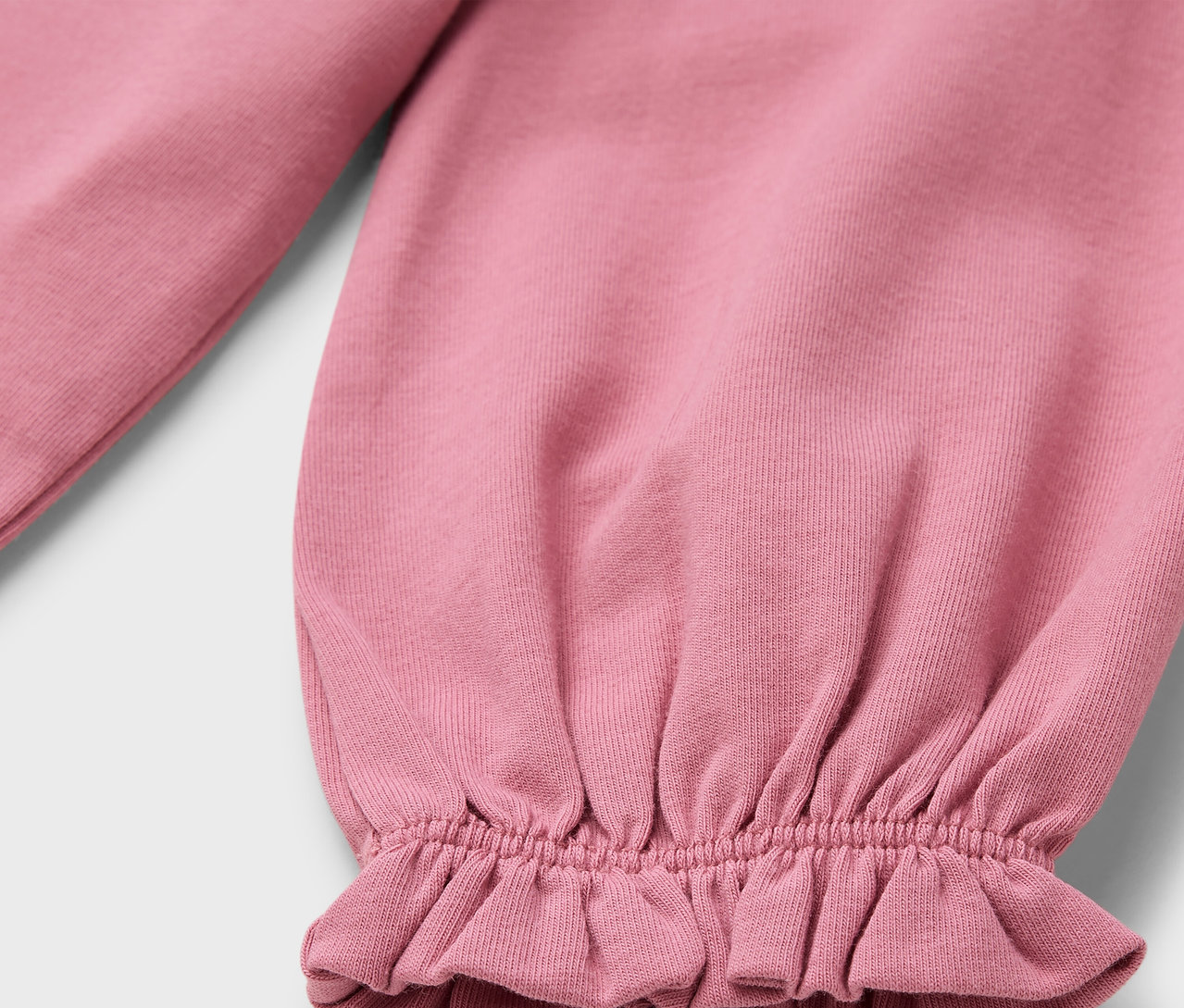 Detal różowego rękawa z falbanką.