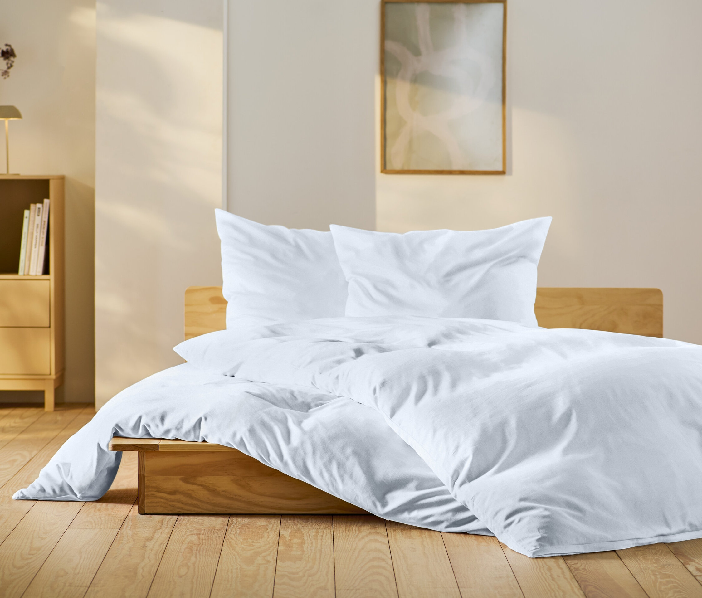 Sypialnia z drewnianym łóżkiem z białą pościelą, drewnianym stolikiem nocnym i dekoracjami.