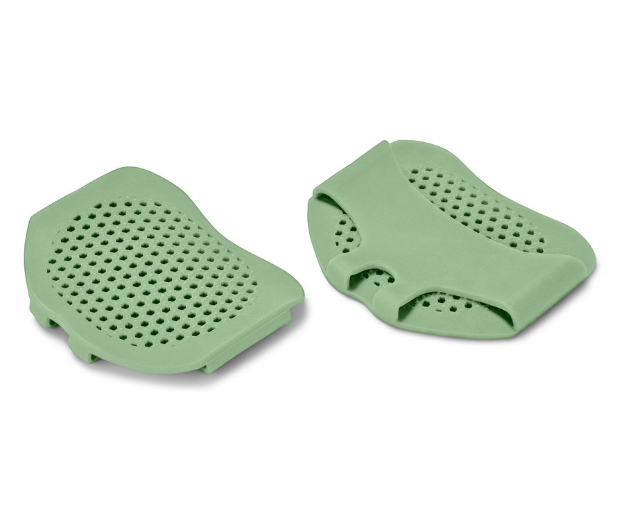 Dwie zielone silikonowe podkładki z perforowaną powierzchnią.