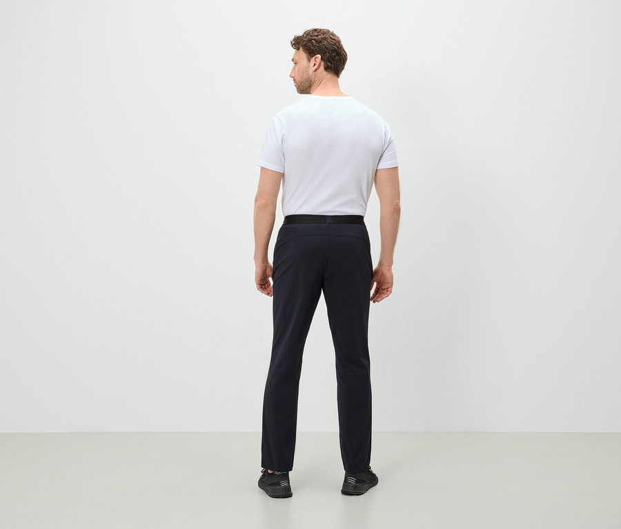 Mężczyzna tyłem do kamery ubrany w białą koszulkę, czarne spodnie i czarne buty.