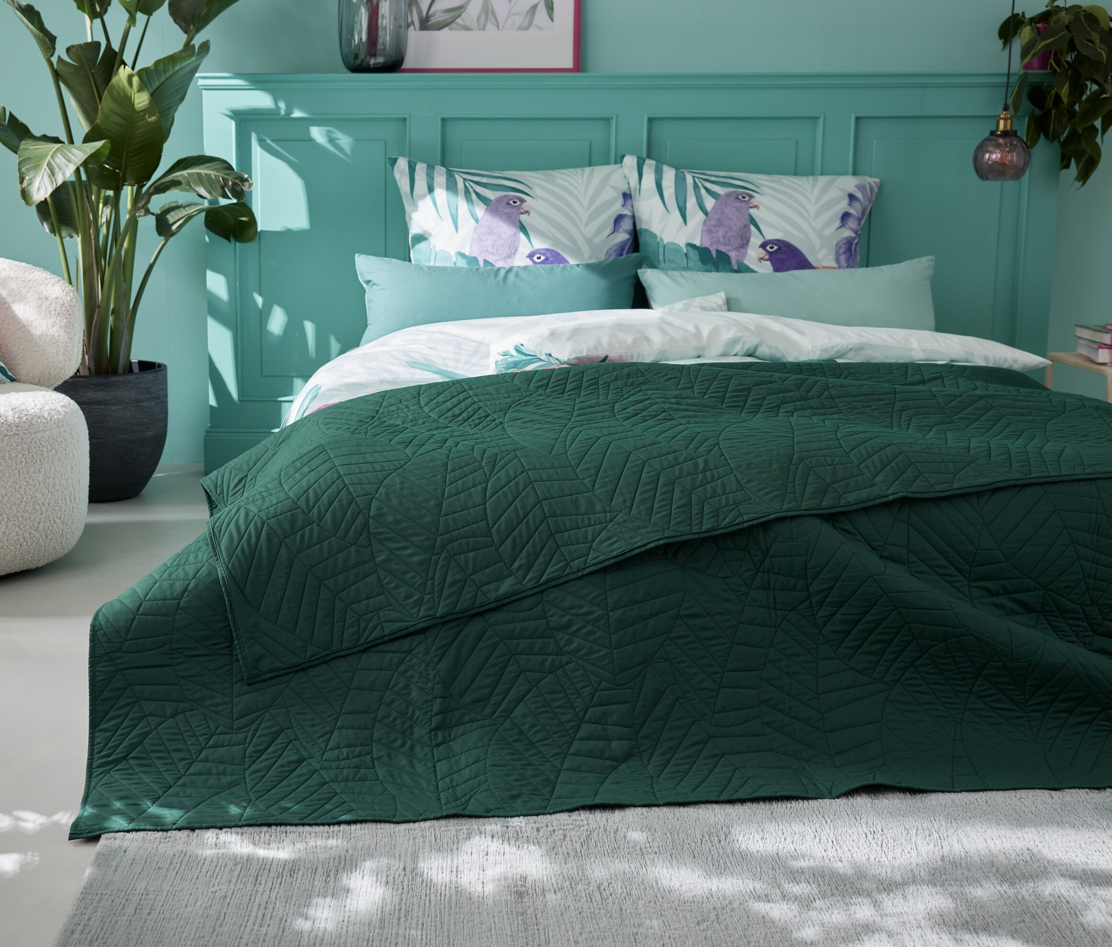 Zielona pikowana narzuta na łóżko (230 x 250 cm) leży na łóżku w sypialni.